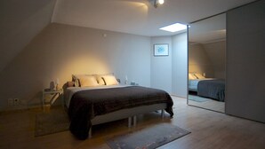 Ein Schlafzimmer mit Bett, Nachttisch, Lampe und einem großen Spiegel.