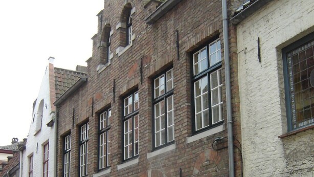 Eine schmale Kopfsteinpflasterstraße, gesäumt von historischen Backsteingebäuden mit großen Rundbogenportalen und traditionellen Fenstern.