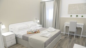 Una habitación de hotel ordenada con cama, mesitas de noche, un escritorio y una silla.