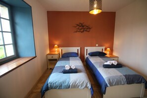 A hotel room with two beds, a window, and a wall-mounted light fixture. - La Maison – Spacious Loire Cottage with Heated Pool near Chinon & Azay le Rideau (Avon-Les-Roches)