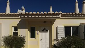 Un bâtiment avec une porte blanche, une petite fenêtre et un balcon doté d’une balustrade blanche.