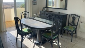 Un coin repas comprenant une table ronde, des chaises, un buffet et un miroir.