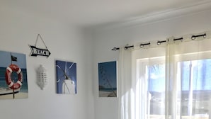 Un salon avec un téléviseur, un canapé, une table basse et des œuvres d’art accrochées au mur.
