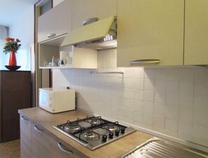 Una cocina compacta con estufa a gas, microondas y un mueble pequeño.