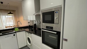 A modern kitchen with a built-in microwave, oven, and washing machine.