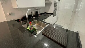 A modern kitchen with a stainless steel sink, black countertop, and white cabinets.