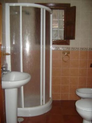 Casa de banho com cabine de duche, lavatório e duas sanitas.