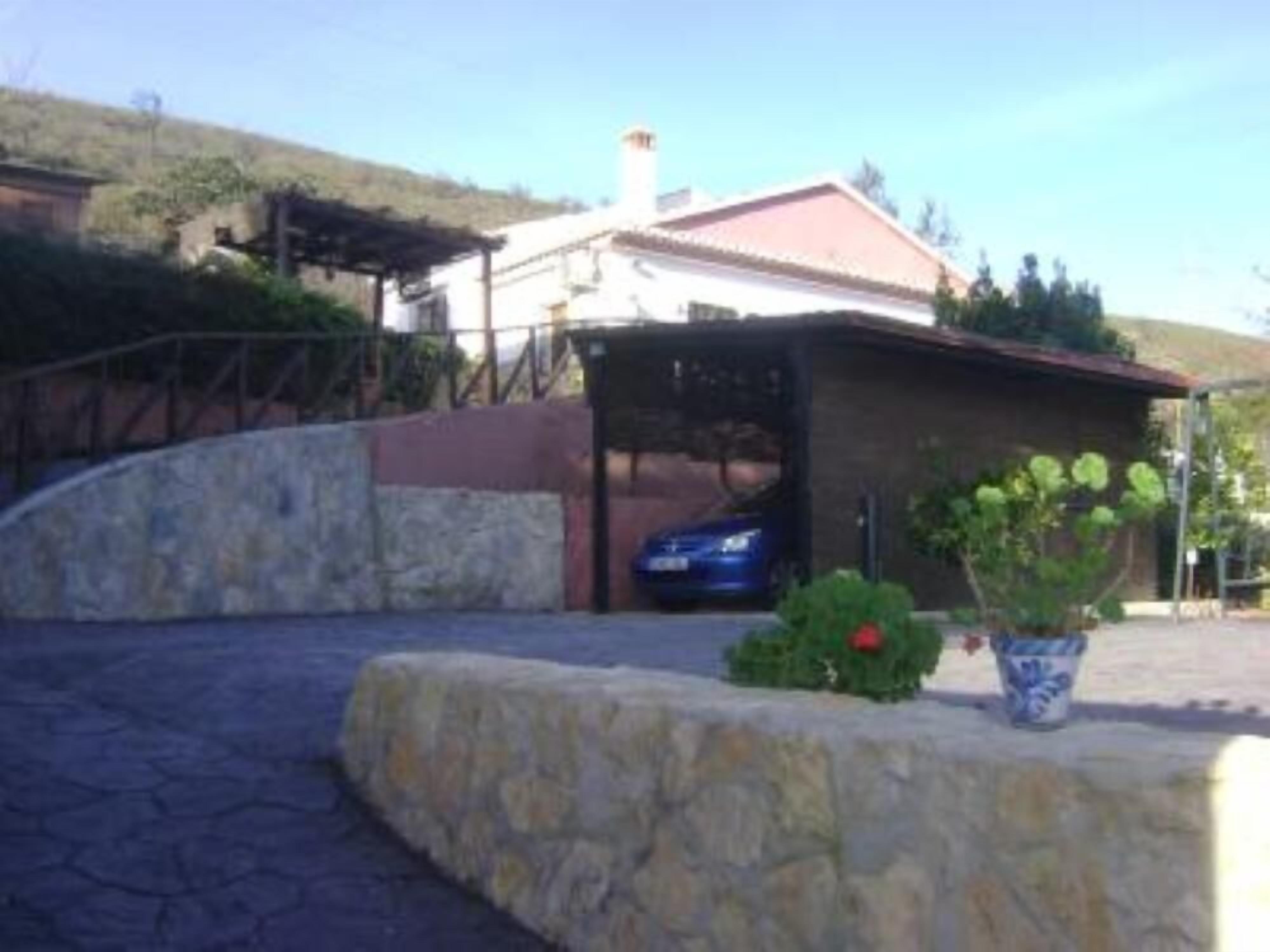 A stone pathway leading to a covered car parking area with a blue car inside.