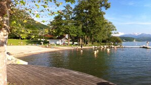 Une terrasse en bois au bord du lac, offrant une vue sur une plage et des arbres.