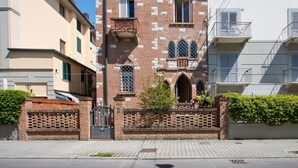 Un edificio histórico con fachada de ladrillo, ventanas arqueadas y una entrada portonada.