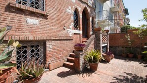 Un edificio de ladrillo con una escalera que lleva a un balcón. Hay plantas en macetas en los escalones y alrededor del edificio.