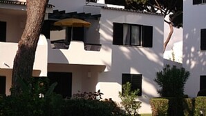 A building with multiple windows and balconies, surrounded by greenery and a tree. - Apartment in the solar sector of Dos Pinheiros, Vilamoura (vilamoura)