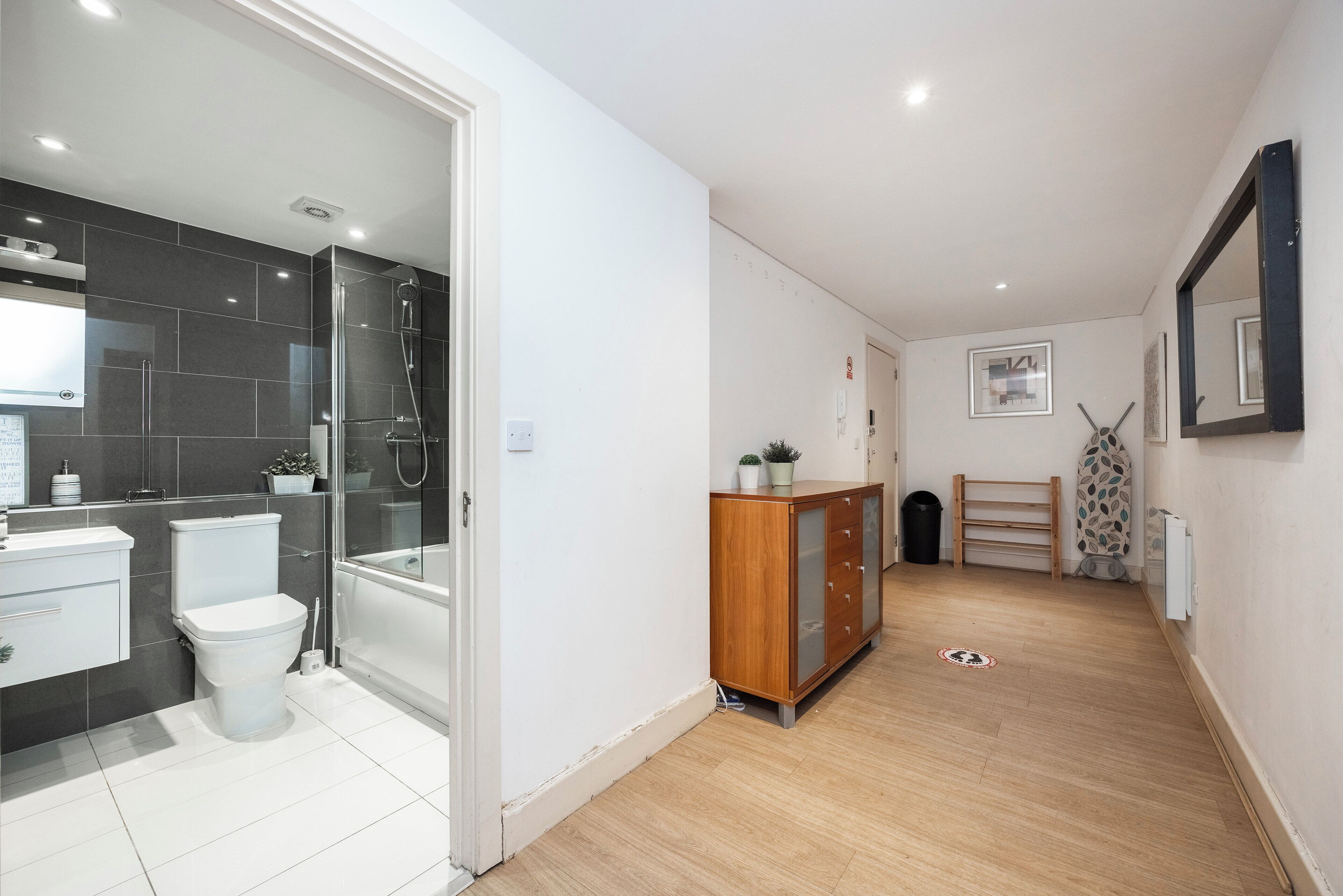 Une salle de bain moderne avec une douche à l’italienne en verre, des toilettes blanches et un meuble en bois.