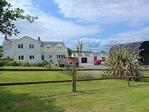 Une maison à deux étages avec une cour clôturée et une voiture rouge garée devant.