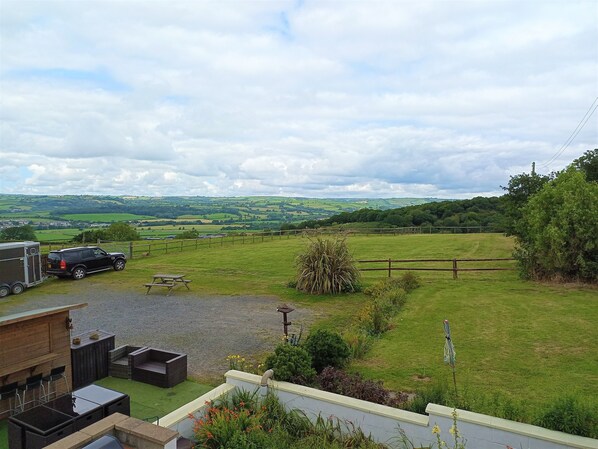 A rural landscape with a fenced yard, a picnic table, and a trailer.