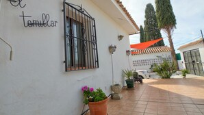 A white building with a metal gate, potted plants, and a tiled patio. - Detached Villa El Tomillar in Frigiliana / Nerja (Frigiliana)