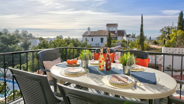 A round table set for two with plates, cutlery, and a bottle on a balcony overlooking a scenic view. - Detached Villa El Tomillar in Frigiliana / Nerja (Frigiliana)