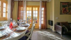 A dining area with a table set for four, a sofa, and a TV on the wall. - Detached Villa El Tomillar in Frigiliana / Nerja (Frigiliana)