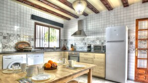 A kitchen with a wooden table, white tiled backsplash, and a white refrigerator. - Detached Villa El Tomillar in Frigiliana / Nerja (Frigiliana)