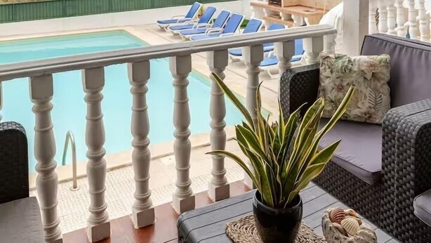 A covered outdoor area with a pool, lounge chairs, and a view of the sea. - Private villa with sea views, private pool and games room (Ericeira)