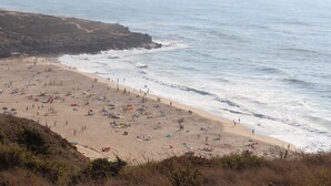 A beach with people, umbrellas, and a rocky coastline. - Private villa with sea views, private pool and games room (Ericeira)