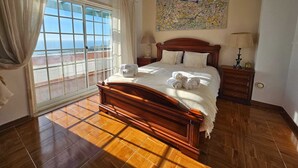 A spacious bedroom with a large bed, a view through a sliding door, and a painting on the wall. - Private villa with sea views, private pool and games room (Ericeira)