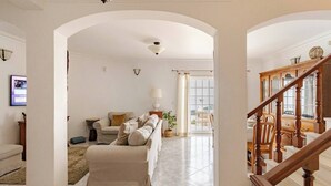 A living room with a sofa, a lamp, a plant, and a staircase. - Private villa with sea views, private pool and games room (Ericeira)