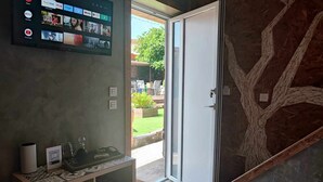 A hotel reception area with a digital screen displaying various streaming services, a small desk with a QR code, and a door leading outside.
