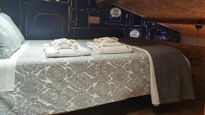 A cozy attic bedroom with a bed, towels, and a dark blue wall with decorative panels.