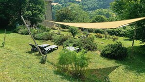 A garden with a hammock, a stone structure, and a view of the surrounding greenery. - Giglio: accommodation in an ancient 18th century farmhouse in the Santerno river valley (Firenzuola)