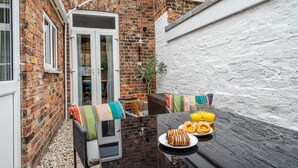 A narrow alleyway with a brick wall, a white door, and a small table with breakfast items. - Buckingham Townhouse -  a family break that sleeps 6 guests in 3 bedrooms (York)
