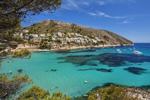 A coastal town with buildings on a hillside overlooking clear turquoise waters.