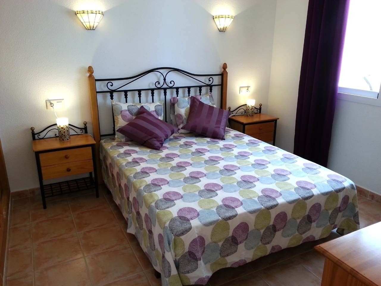 Une chambre à coucher avec un lit, deux tables de chevet et une commode.