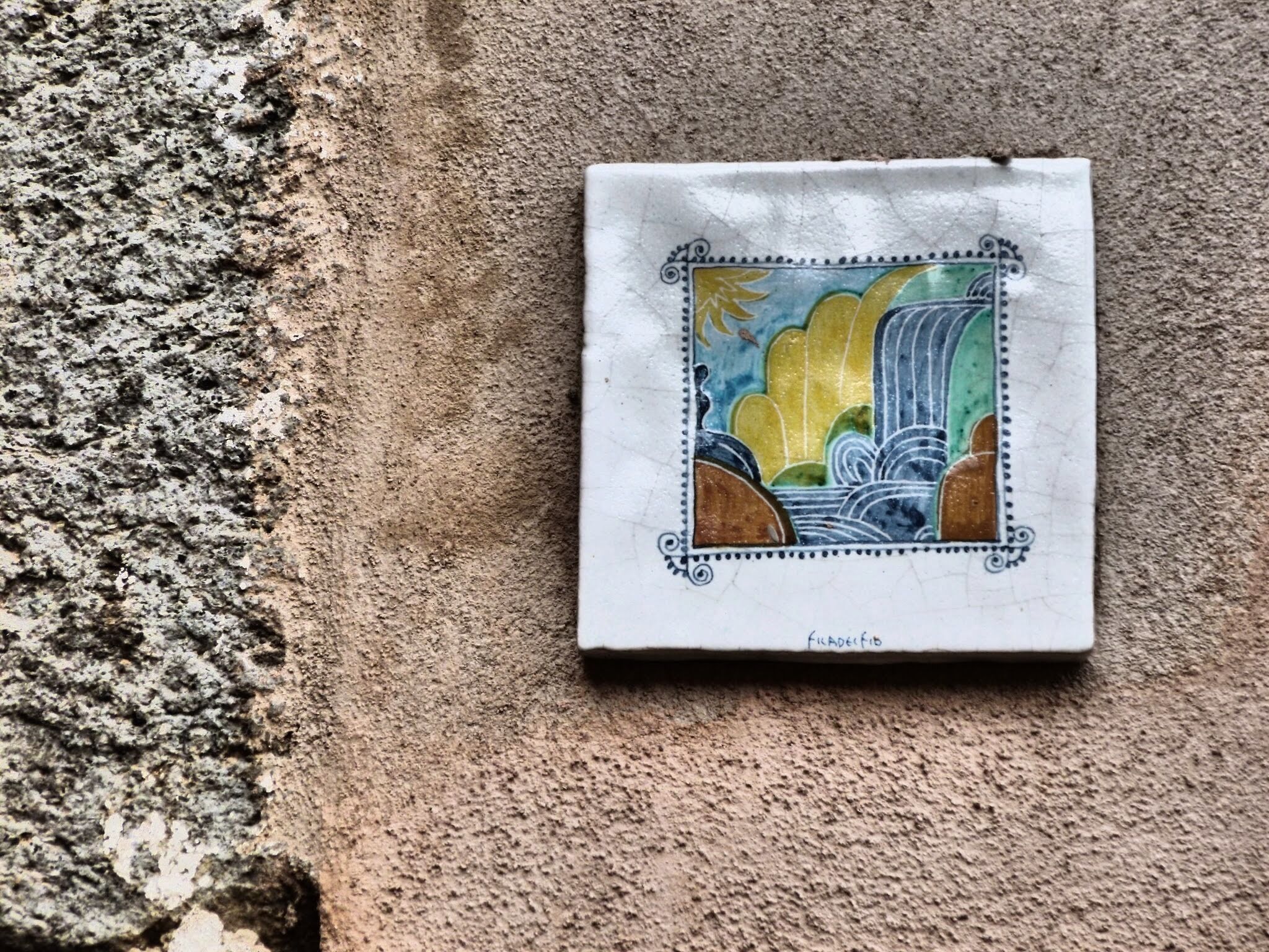 A tile with a colorful landscape design, featuring a waterfall and mountains.