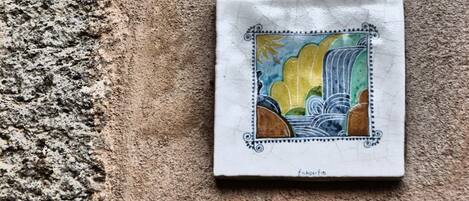 A tile with a colorful landscape design, featuring a waterfall and mountains.