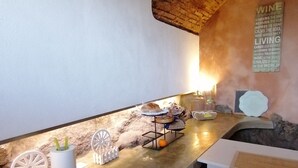 Un coin bar au style rustique, avec un mur en pierre, un comptoir en bois et un panneau d’information sur le vin.