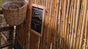 Une clôture en bambou, un panier en osier et un panneau noir sur lequel on peut lire : « Etta Shower ».