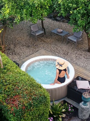 Un jacuzzi rodeado por una terraza de madera, con una silla y una mesa cerca.