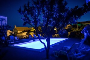 Un espace piscine avec des chaises longues et un arbre au premier plan.