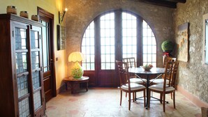 A dining area with a large arched window, wooden furniture, and a lamp on a small table. - BEAUTIFUL VILLA with SWIMMING POOL for EXCLUSIVE use, relax a few km from the sea! (Carini)