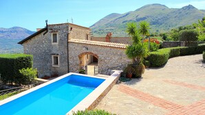 A stone building with a swimming pool, surrounded by greenery and mountains in the background. - BEAUTIFUL VILLA with SWIMMING POOL for EXCLUSIVE use, relax a few km from the sea! (Carini)