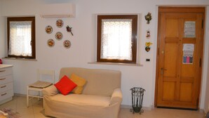 A room with a beige sofa, a white chair, a wooden door, and decorative plates on the wall. - new renovated apartment 3 rooms - 2/5 persons, modern and well furnished. 8 minuts walk to S. Marco - (Venezia)