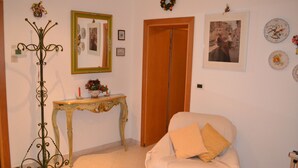 A room with a white armchair, a wooden door, a mirror, and a decorative stand. - new renovated apartment 3 rooms - 2/5 persons, modern and well furnished. 8 minuts walk to S. Marco - (Venezia)