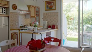 A kitchen with a dining area, a window with a view of the outdoors, and a red tablecloth. - Apartment *** with terrace and swimming pool in secure luxury residence (Saint-Rémy-De-Provence)
