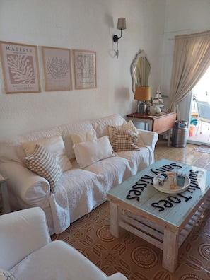 A cozy living room with a white sofa, a wooden coffee table with a tray, and framed artwork on the wall.