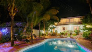 Ein Schwimmbecken mit Liegestühlen und ein Gebäude mit Balkon im Hintergrund.