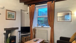 Un salón acogedor con chimenea, televisor y ventana con cortinas.