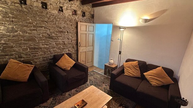 Una sala de estar acogedora con dos sofás, una mesa de centro y una pared de piedra.