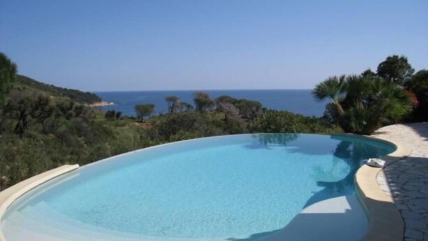 Une piscine privée offrant une vue dégagée sur l’océan et la végétation environnante.