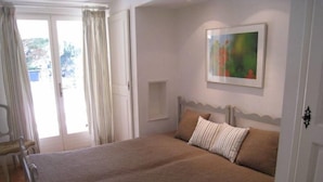 Une chambre avec un grand lit, une chaise, une porte et une fenêtre avec des rideaux.